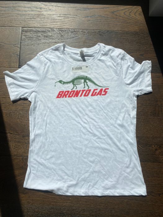 White shirt with green dinosaur brontosaurus skeleton with red text below that reads: "Bronto Gas"